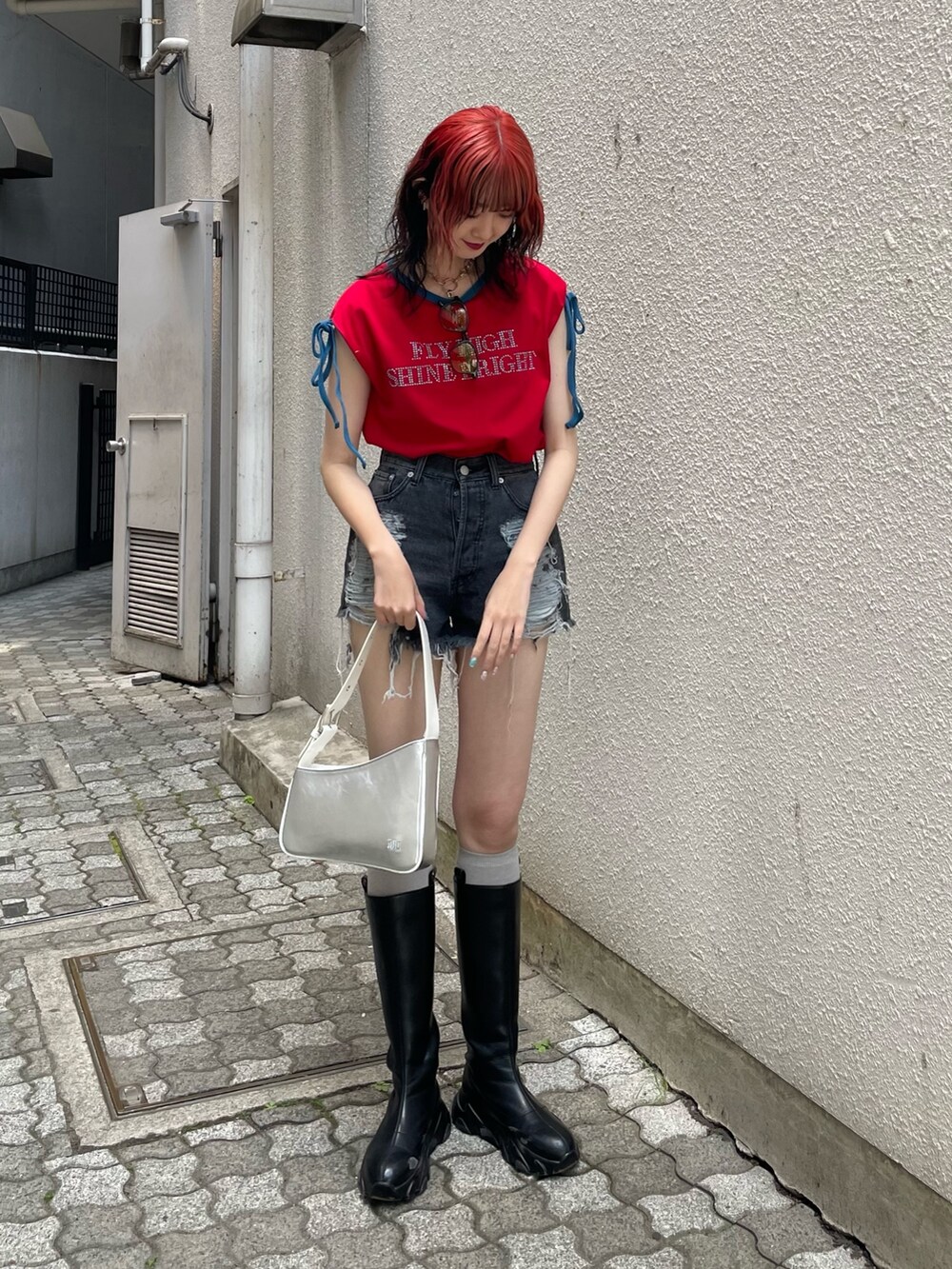 ブラック系のデニムパンツ、シルバー系のハンドバッグ、レッド系のTシャツ/カットソーを着用したレディースの夏コーディネートの2枚目の写真