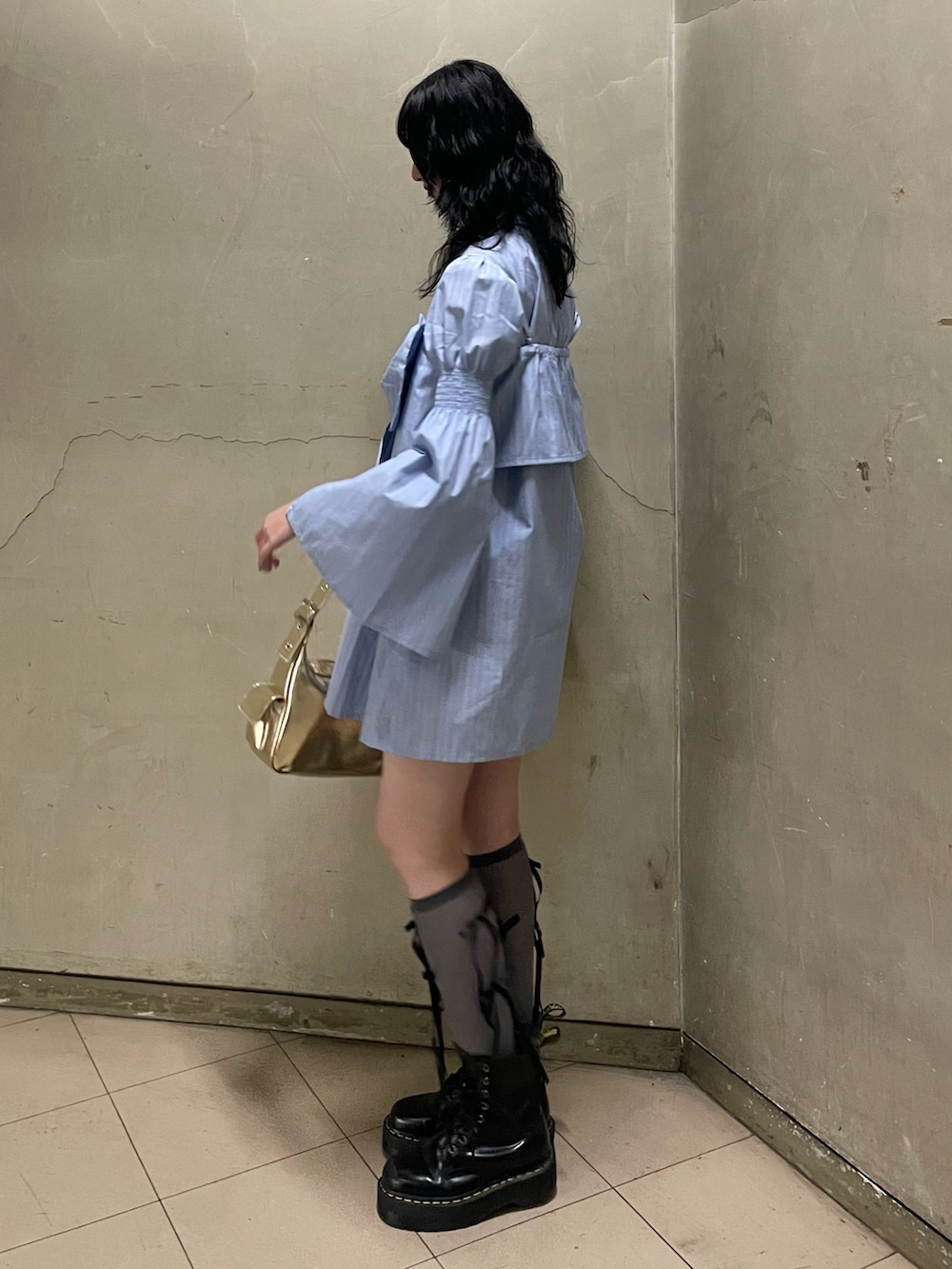 ブルー系のシャツワンピース、ゴールド系のハンドバッグ、ブラック系のブーツを着用したレディースの夏コーディネートの3枚目の写真