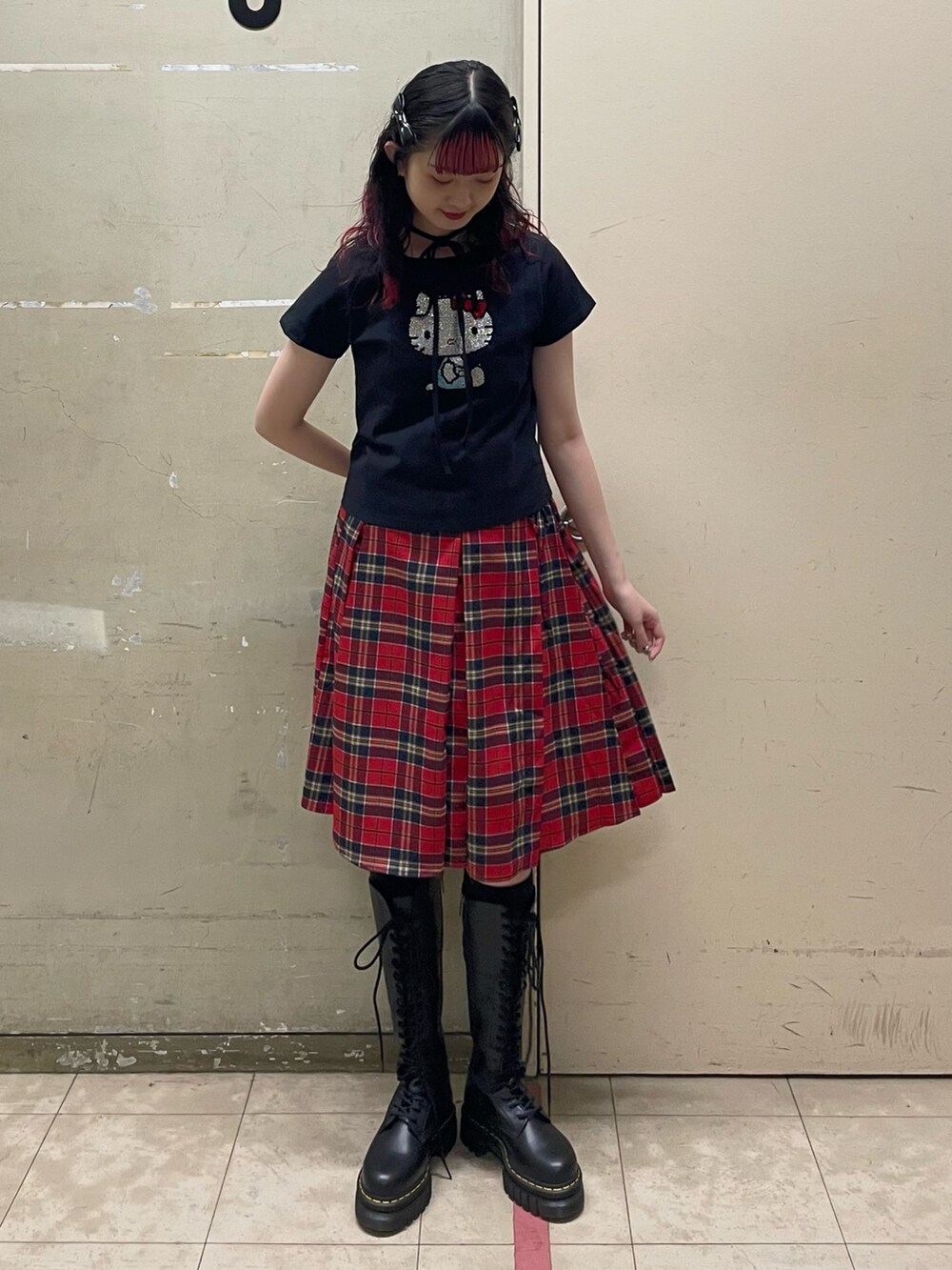 ブラック系のTシャツ/カットソー、レッド系のスカート、ブラック系のブーツを着用したレディースの春コーディネートの2枚目の写真