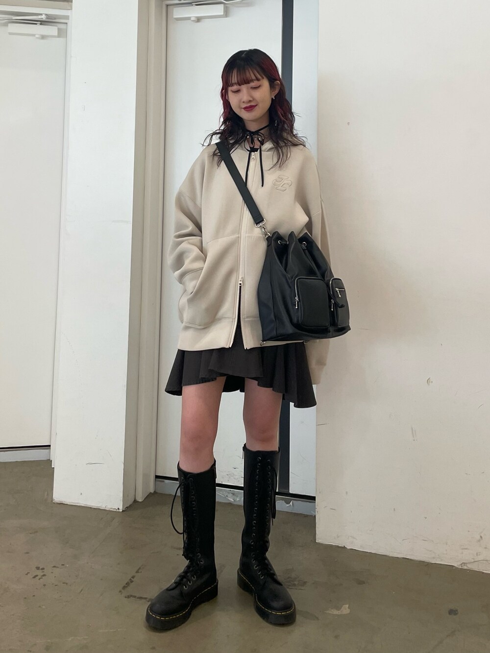 ホワイト系のパーカー、ブラック系のバックパック/リュック、ブラック系のスカートを着用したレディースの冬コーディネートの2枚目の写真