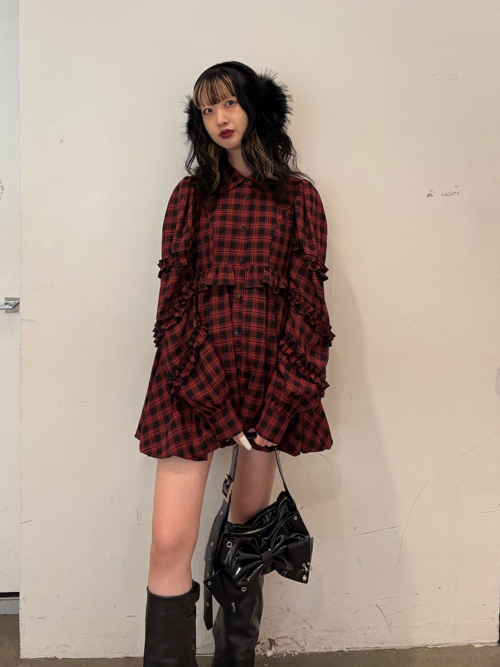 レッド系のワンピース、ブラック系のショルダーバッグ、ブラック系のブーツを着用したレディースの秋コーディネートの4枚目の写真