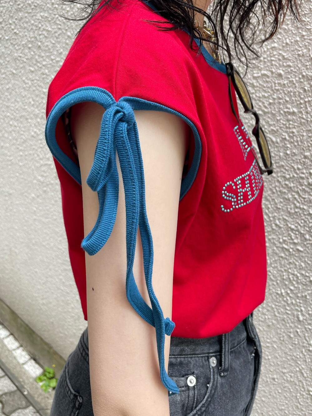 ブラック系のデニムパンツ、シルバー系のハンドバッグ、レッド系のTシャツ/カットソーを着用したレディースの夏コーディネートの6枚目の写真