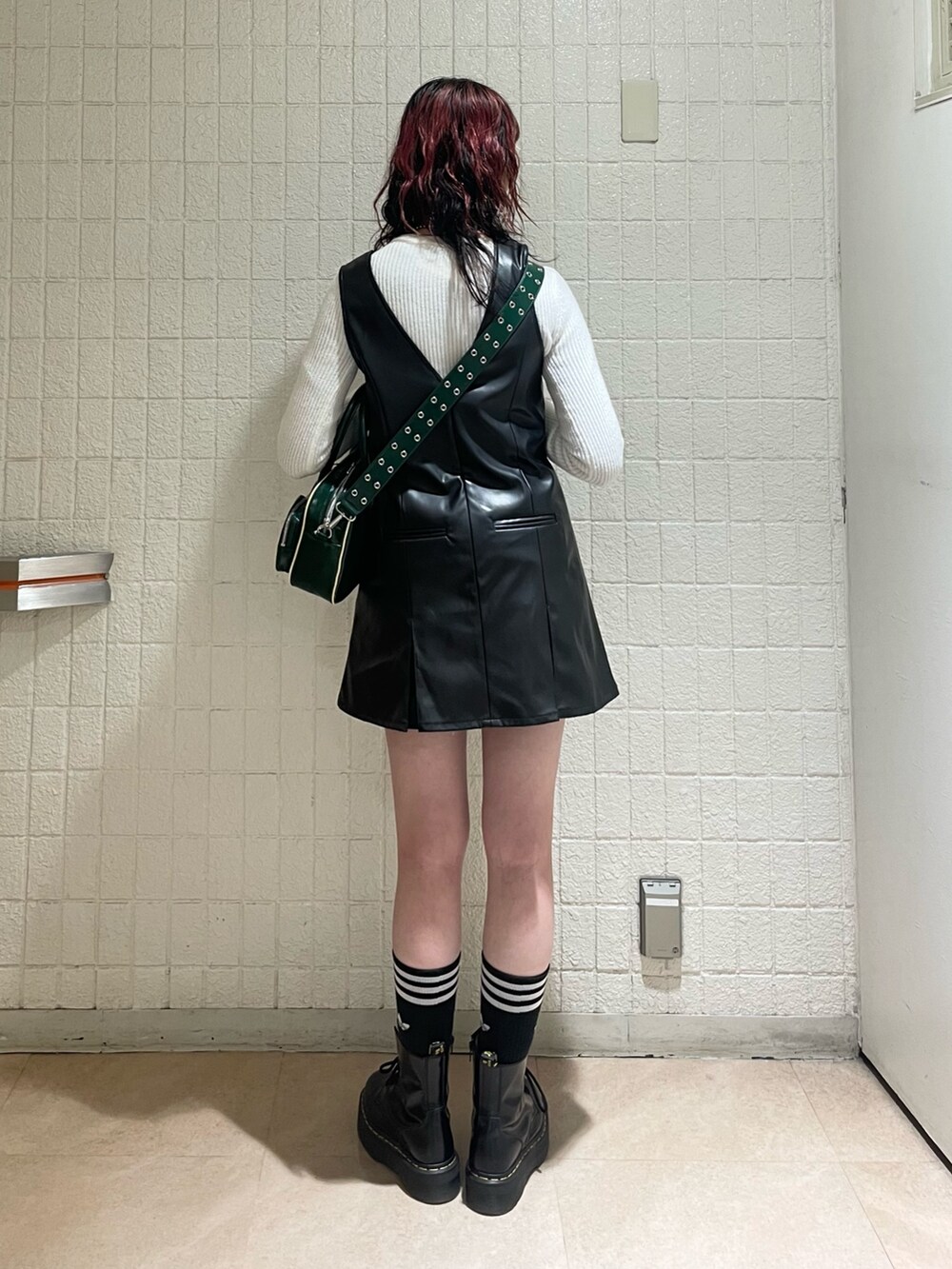 パープル系のブルゾン、ホワイト系のニット/セーター、ブラック系のジャンパースカートを着用したレディースの秋コーディネートの4枚目の写真