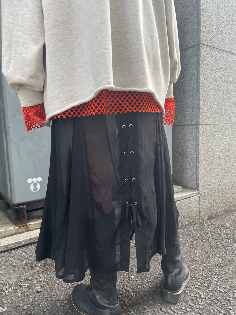 ブラック系のブーツ、ブラック系のスカート、オレンジ系のTシャツ/カットソーを着用したレディースの春コーディネートの9枚目の写真