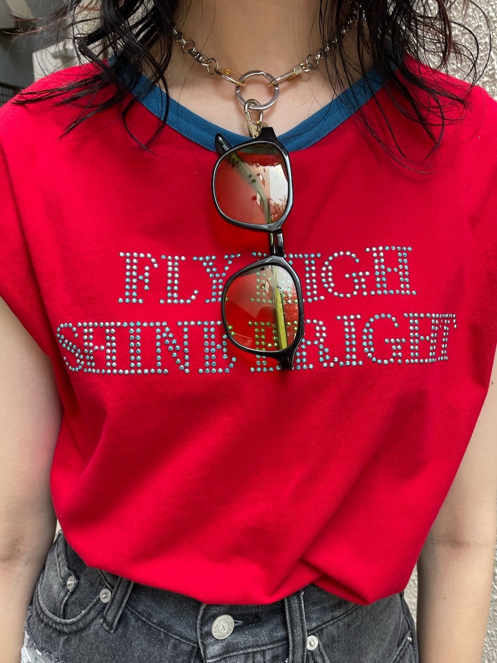 ブラック系のデニムパンツ、シルバー系のハンドバッグ、レッド系のTシャツ/カットソーを着用したレディースの夏コーディネートの5枚目の写真