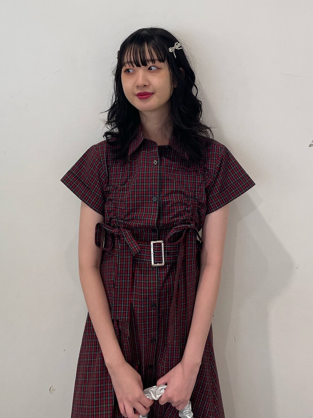 レッド系のワンピース、シルバー系のハンドバッグ、ブラック系のブーツを着用したレディースの春コーディネートの4枚目の写真