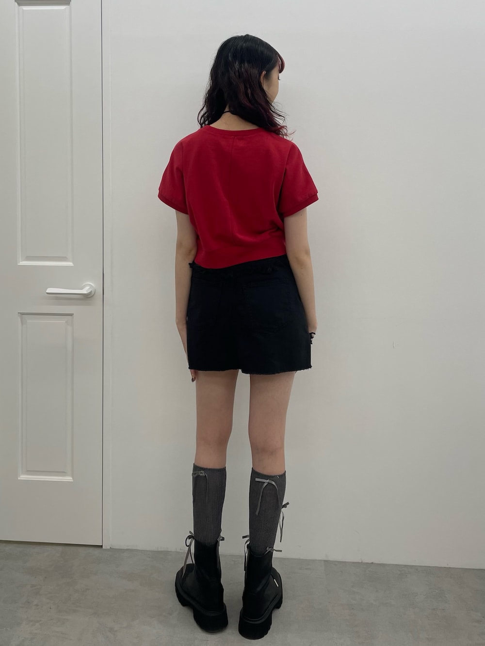 レッド系のTシャツ/カットソー、ブラック系のスカート、ブラック系のブーツを着用したレディースの夏コーディネートの3枚目の写真