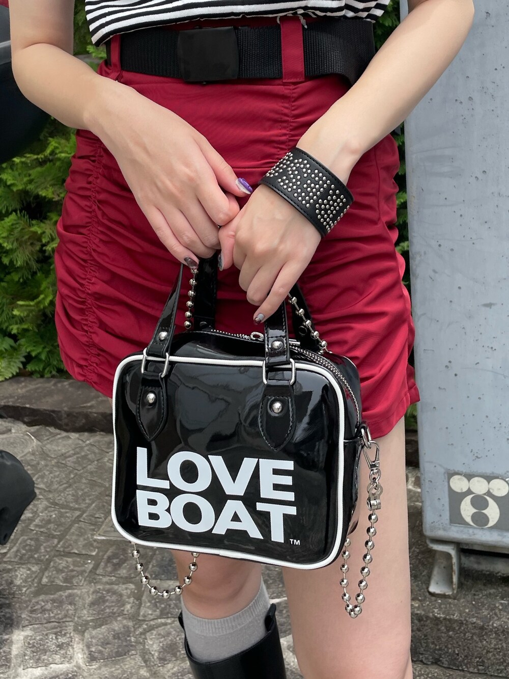 ホワイト系のニット/セーター、ブラック系のボストンバッグ、レッド系のスカートを着用したレディースの夏コーディネートの7枚目の写真