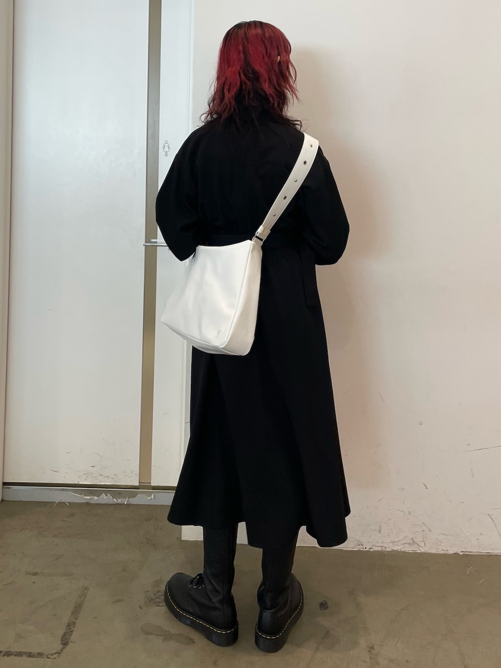 ホワイト系のショルダーバッグ、ブラック系のワンピース、ブラック系のブーツを着用したレディースの冬コーディネートの3枚目の写真