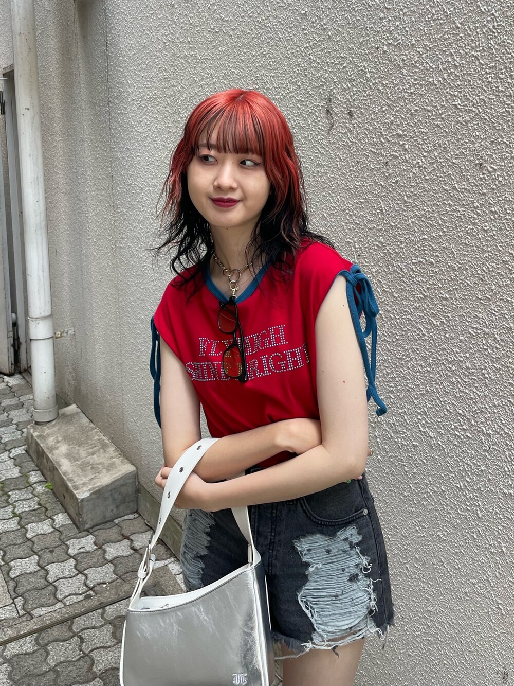 ブラック系のデニムパンツ、シルバー系のハンドバッグ、レッド系のTシャツ/カットソーを着用したレディースの夏コーディネートの4枚目の写真