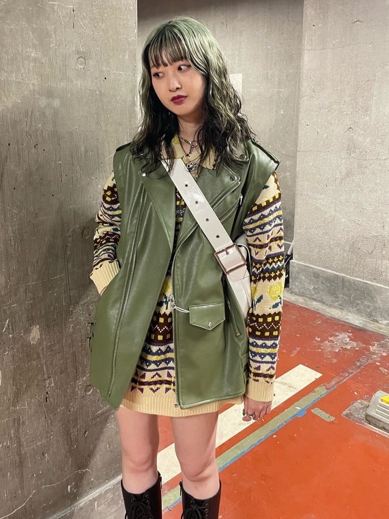 ブラック系のブーツ、ホワイト系のハンドバッグ、グリーン系のライダースジャケットを着用したレディースの秋コーディネートの4枚目の写真