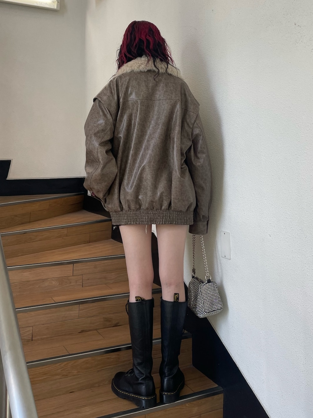 ブラック系のデニムパンツ、ブラウン系のブルゾン、ホワイト系のTシャツ/カットソーを着用したレディースの秋コーディネートの3枚目の写真