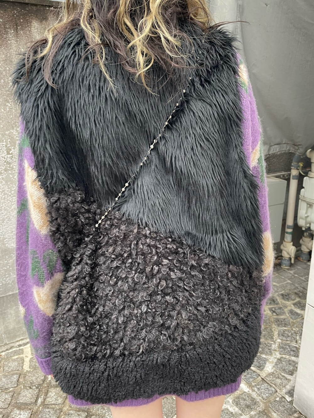 パープル系のニット/セーター、ホワイト系のショルダーバッグ、ブラック系のベストを着用したレディースの冬コーディネートの6枚目の写真