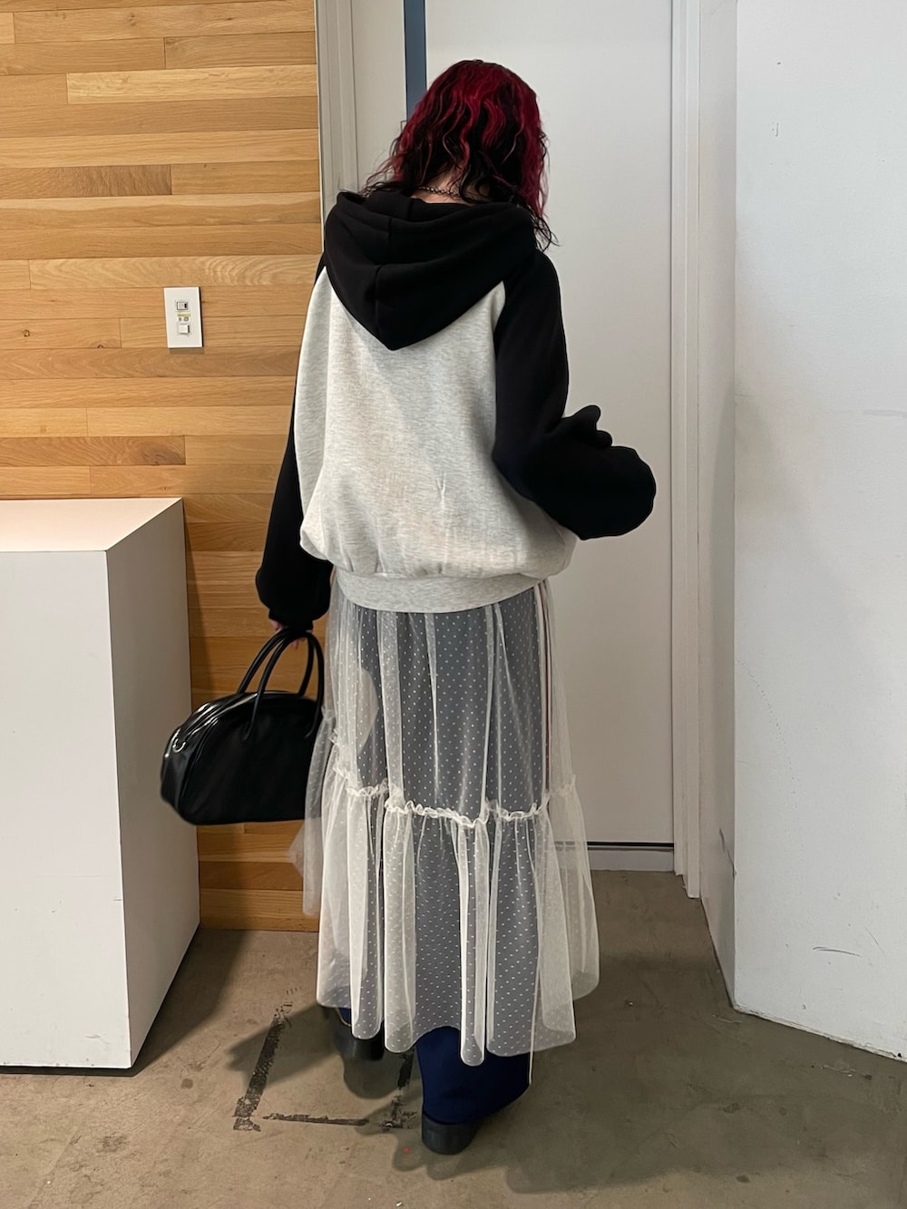 グレー系のパーカー、ホワイト系のワンピース、ブラック系のボストンバッグを着用したレディースの冬コーディネートの3枚目の写真