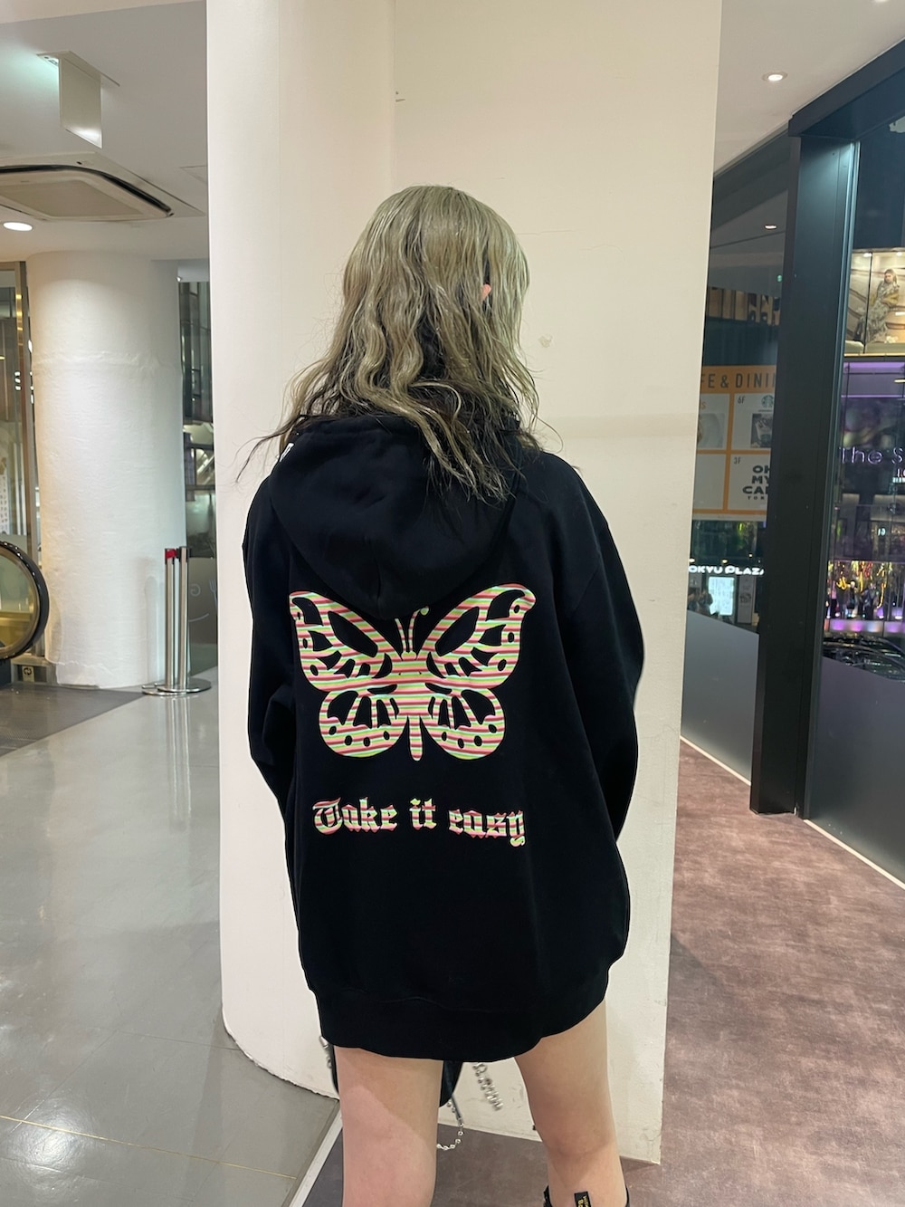 イエロー系のチェスターコート、ブラック系のパーカー、ブラック系のショルダーバッグを着用したレディースの冬コーディネートの6枚目の写真