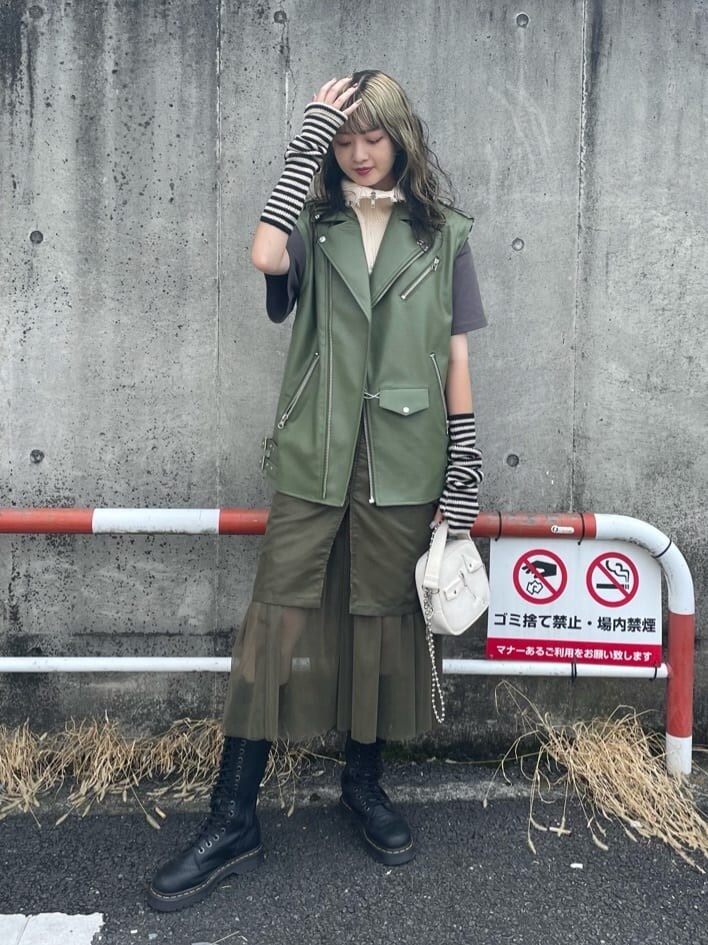 ブラック系のブーツ、ベージュ系のスカート、ホワイト系のベストを着用したレディースの秋コーディネートの2枚目の写真