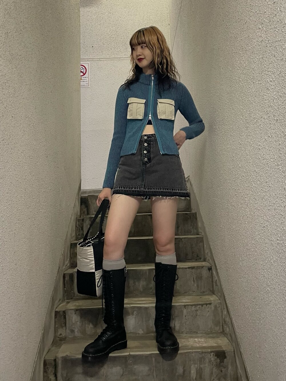 ブルー系のニット/セーター、ブラック系のデニムパンツ、ホワイト系のトートバッグを着用したレディースの秋コーディネートの2枚目の写真