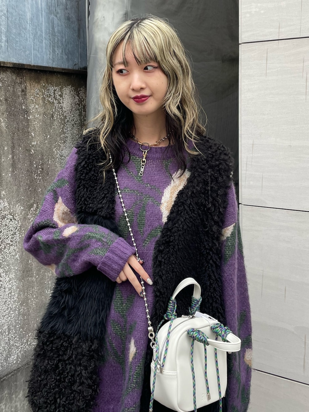 パープル系のニット/セーター、ホワイト系のショルダーバッグ、ブラック系のベストを着用したレディースの冬コーディネートの3枚目の写真