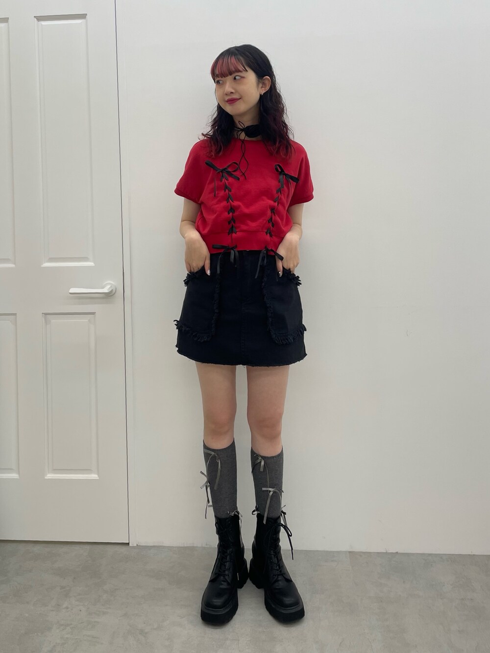 レッド系のTシャツ/カットソー、ブラック系のスカート、ブラック系のブーツを着用したレディースの夏コーディネートの2枚目の写真