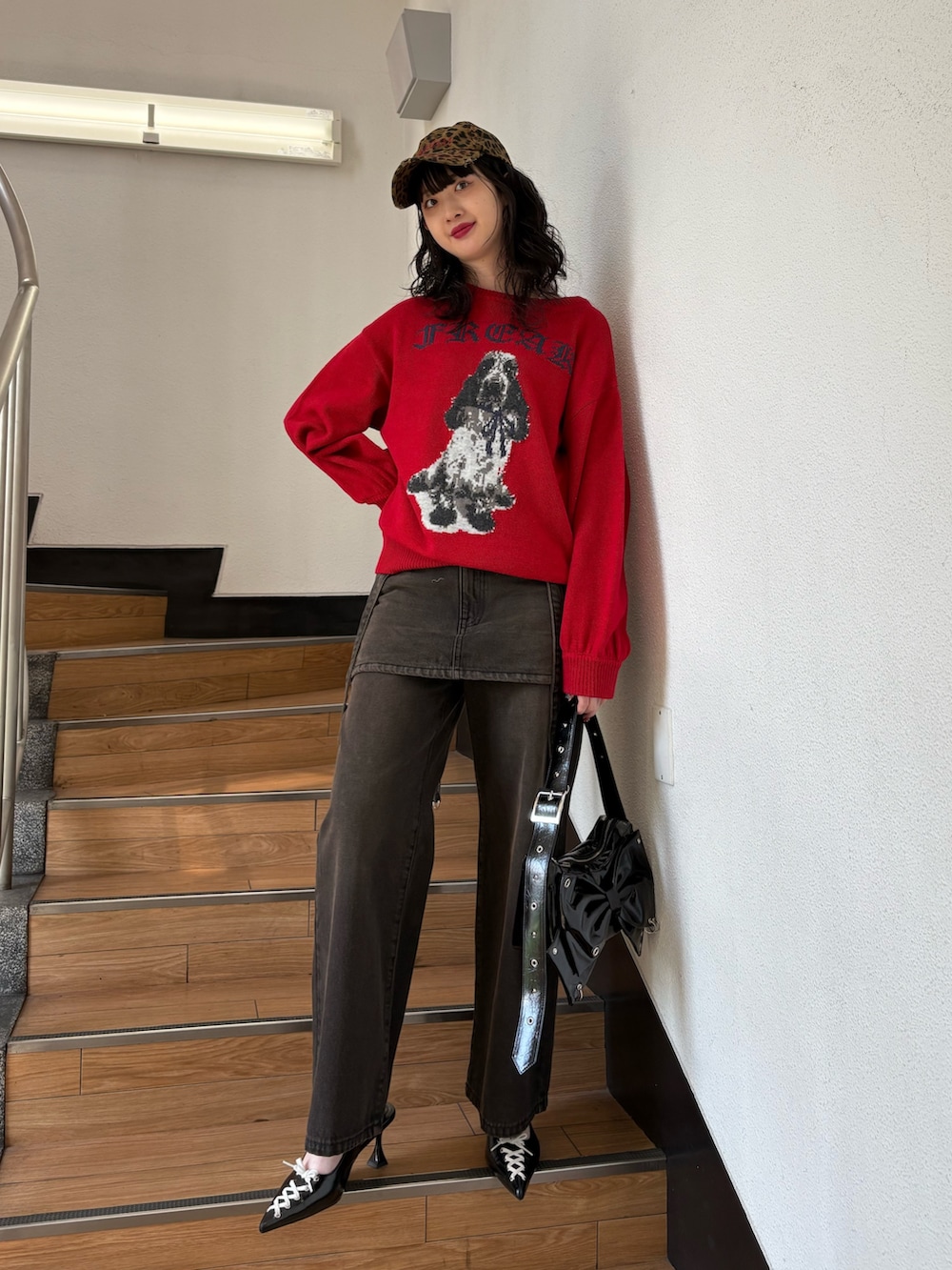 レッド系のニット/セーター、ブラック系のデニムパンツ、ブラック系のショルダーバッグを着用したレディースの秋コーディネートの2枚目の写真