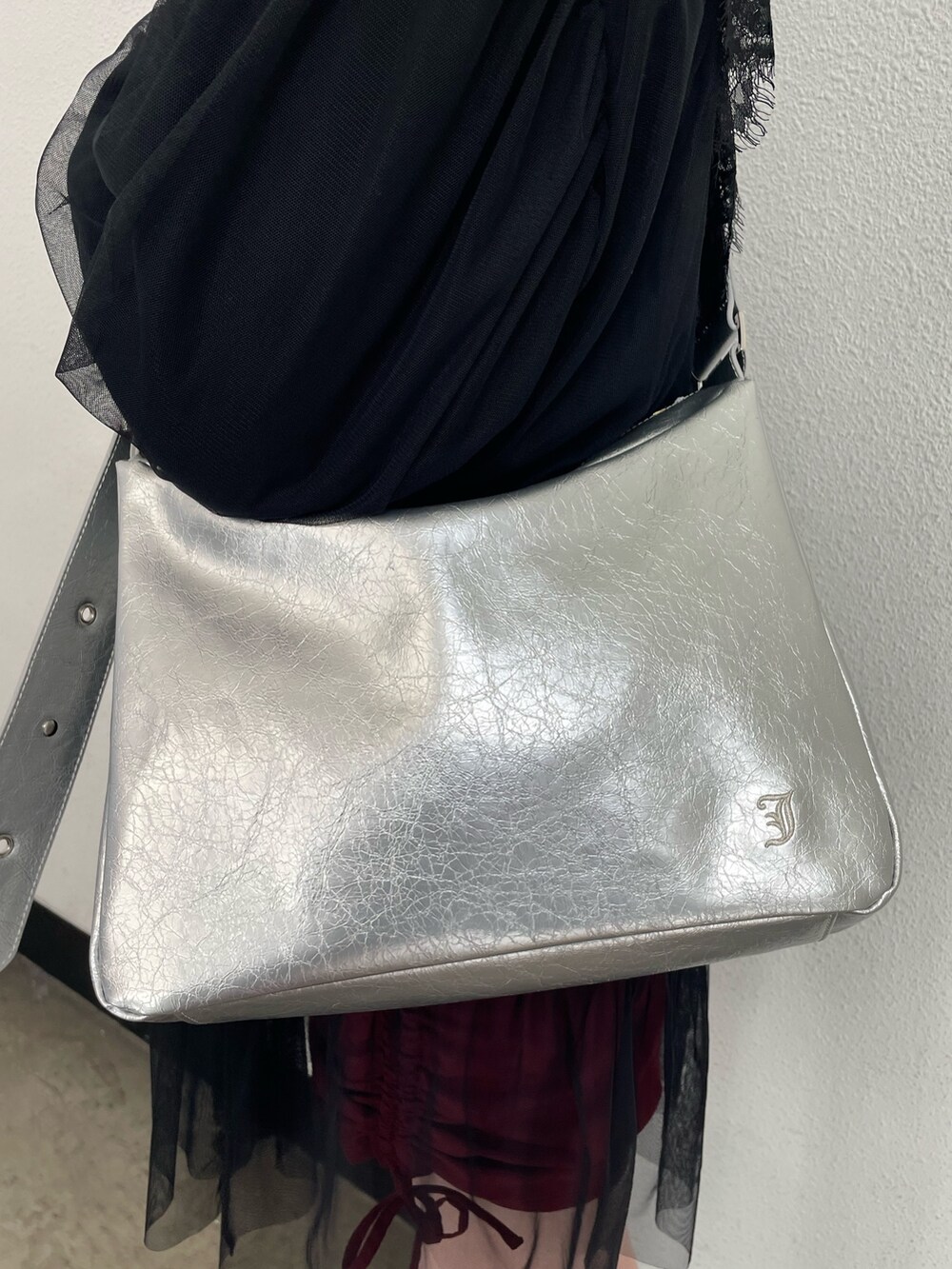 ブラック系のワンピース、レッド系のスカート、シルバー系のショルダーバッグを着用したレディースの冬コーディネートの7枚目の写真