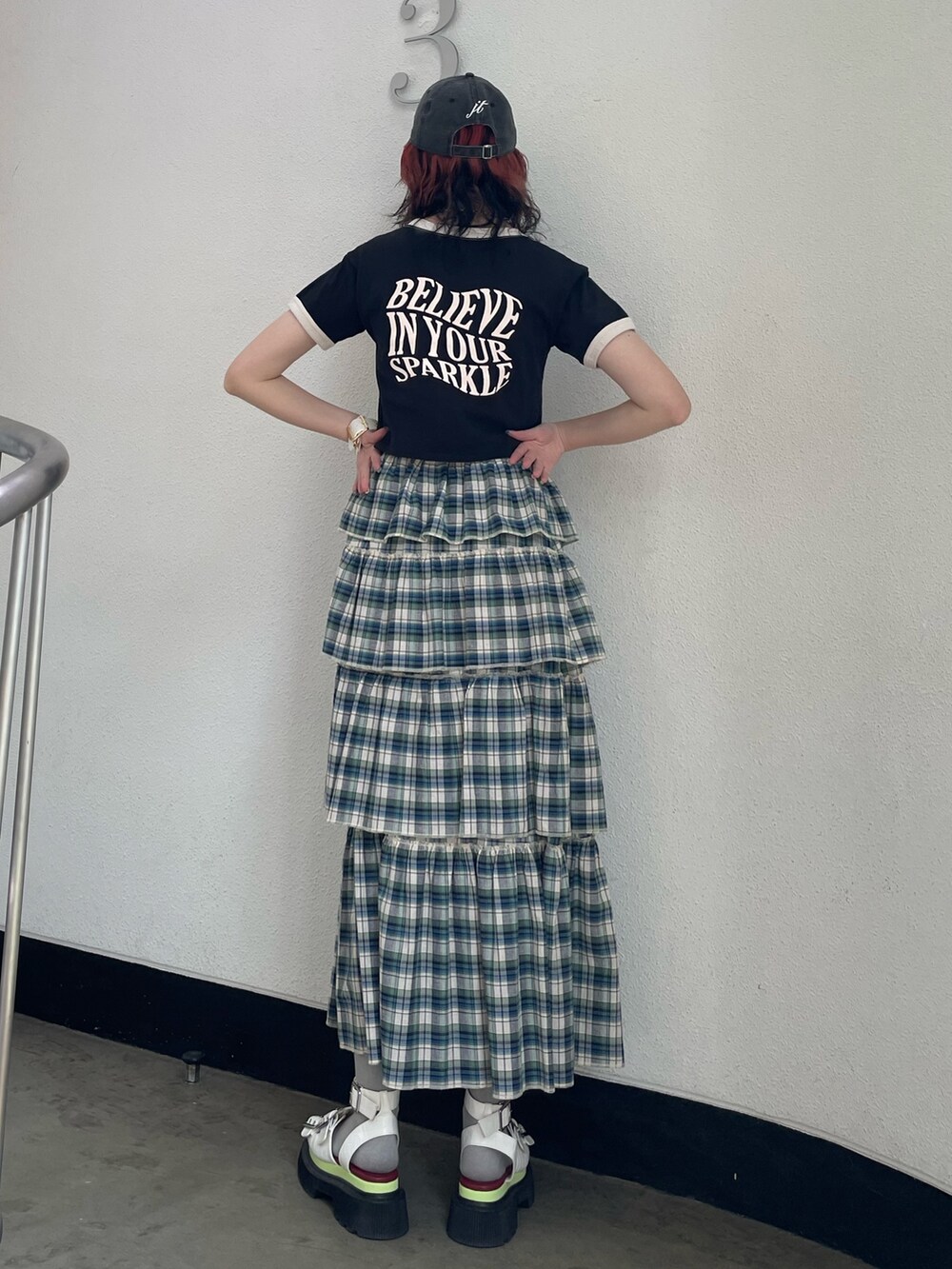 グリーン系のスカート、ブラック系のTシャツ/カットソー、ホワイト系のサンダルを着用したレディースの夏コーディネートの3枚目の写真