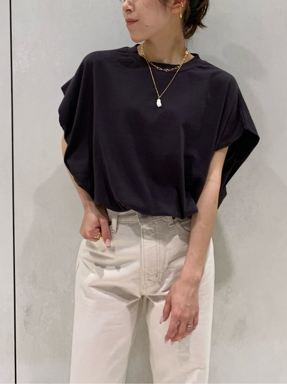 ホワイト系のデニムパンツ、ブラック系のTシャツ/カットソー、オレンジ系のサンダルを着用したレディースの春コーディネートの4枚目の写真