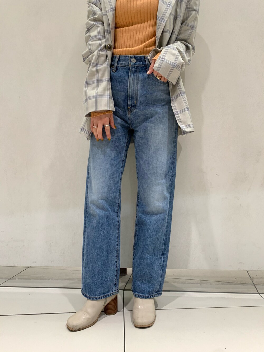 ブルー系のテーラードジャケット、ブルー系のデニムパンツ、オレンジ系のニット/セーターを着用したレディースの冬コーディネートの2枚目の写真