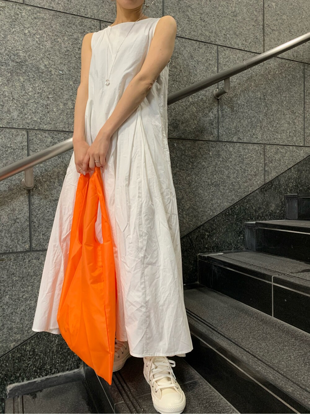 オレンジ系のハンドバッグ、ホワイト系のワンピースを着用したレディースの春コーディネートの5枚目の写真