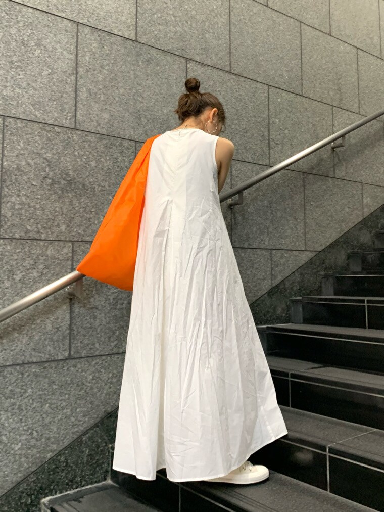 オレンジ系のハンドバッグ、ホワイト系のワンピースを着用したレディースの春コーディネートの3枚目の写真