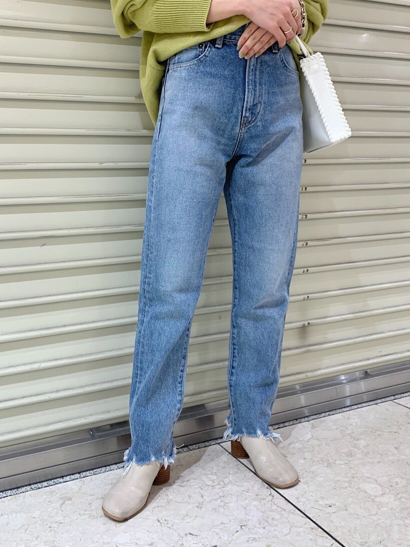 ブルー系のデニムパンツ、ホワイト系のショルダーバッグ、グリーン系のニット/セーターを着用したレディースの冬コーディネートの2枚目の写真