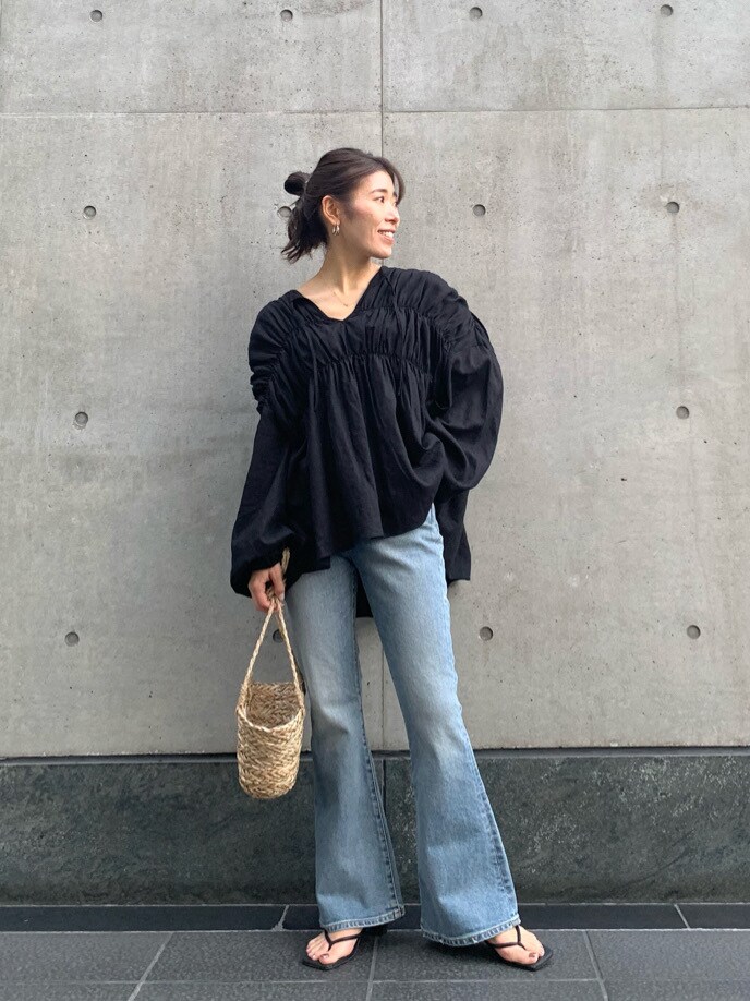 ブラック系のシャツ/ブラウス、ベージュ系のかごバッグ、ブルー系のデニムパンツを着用したレディースの春コーディネートの2枚目の写真