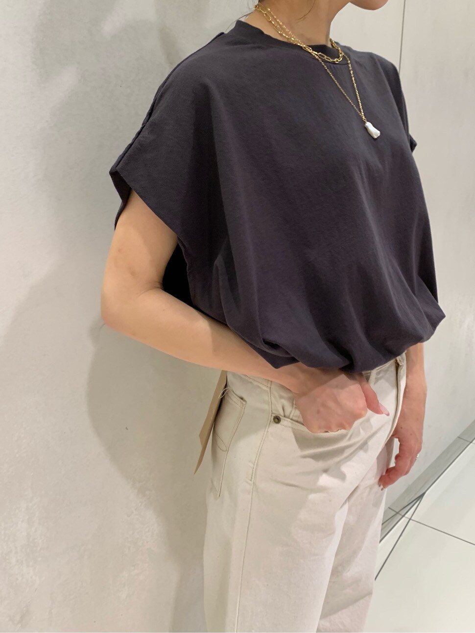 ホワイト系のデニムパンツ、ブラック系のTシャツ/カットソー、オレンジ系のサンダルを着用したレディースの春コーディネートの5枚目の写真