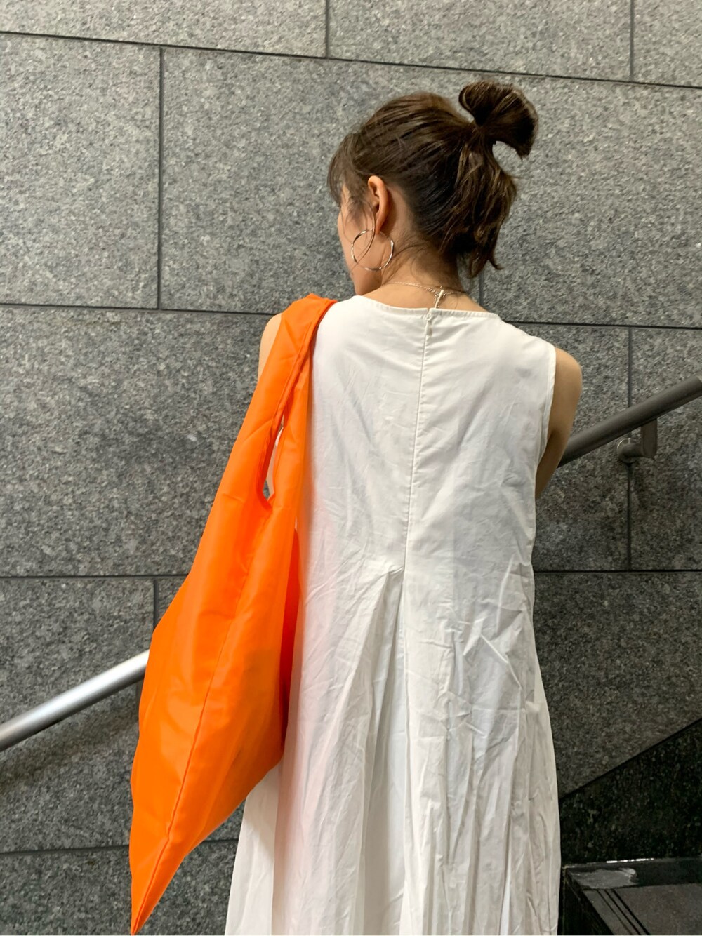 オレンジ系のハンドバッグ、ホワイト系のワンピースを着用したレディースの春コーディネートの6枚目の写真