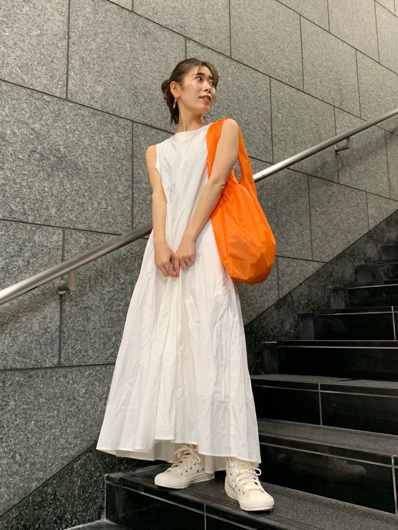 オレンジ系のハンドバッグ、ホワイト系のワンピースを着用したレディースの春コーディネートの2枚目の写真