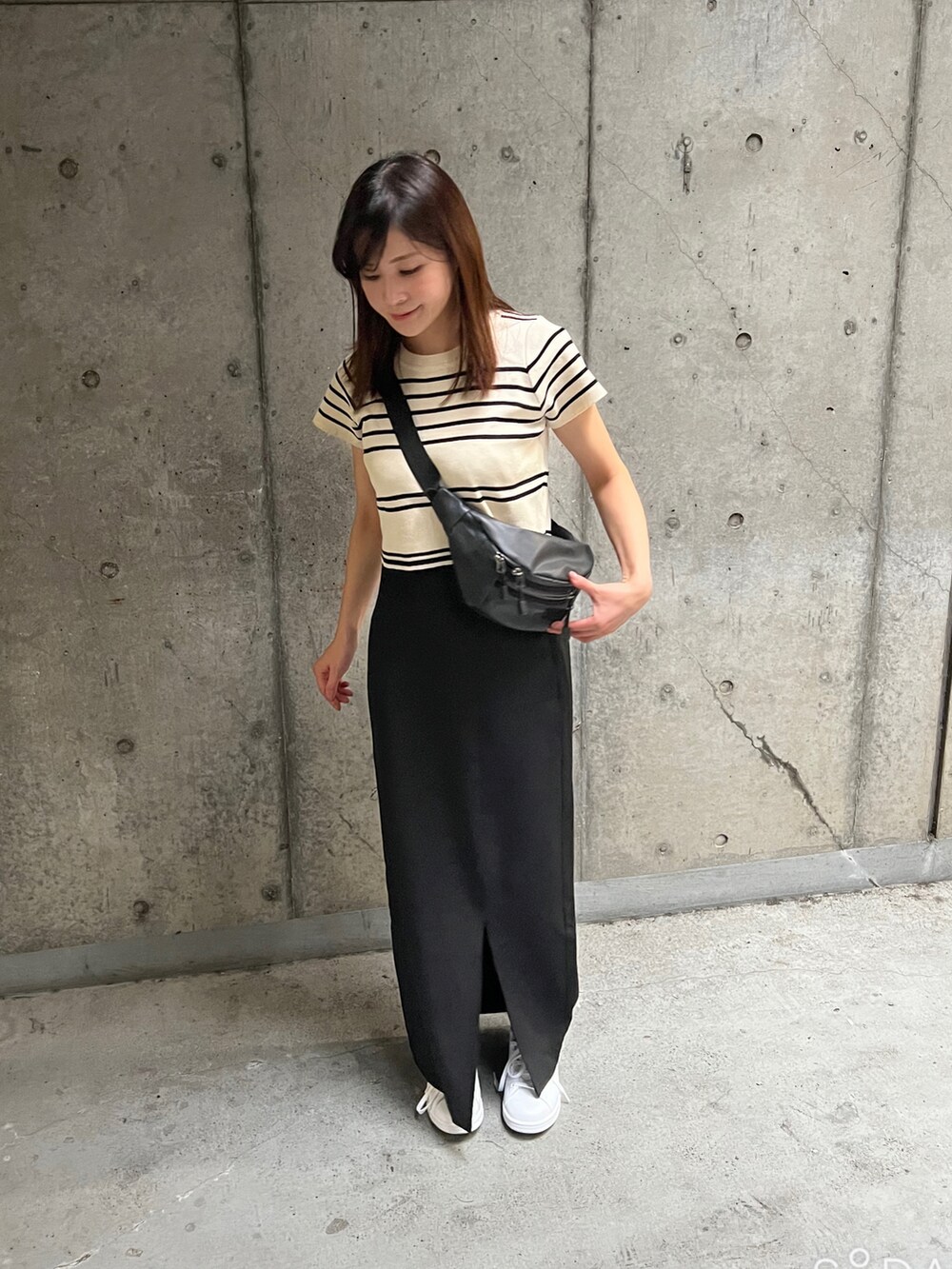 ホワイト系のトップス、ブラック系のスカート、ホワイト系のスニーカーを着用したレディースの夏コーディネートの2枚目の写真
