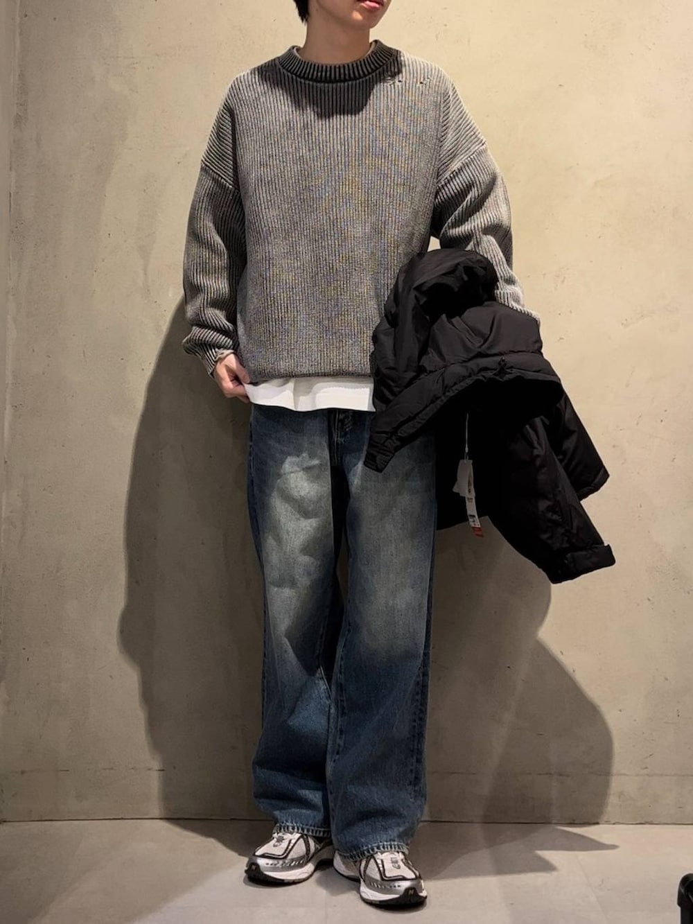 ブラック系のダウンジャケット/コート、グレー系のニット/セーター、ブルー系のデニムパンツを着用したメンズの冬コーディネートの2枚目の写真