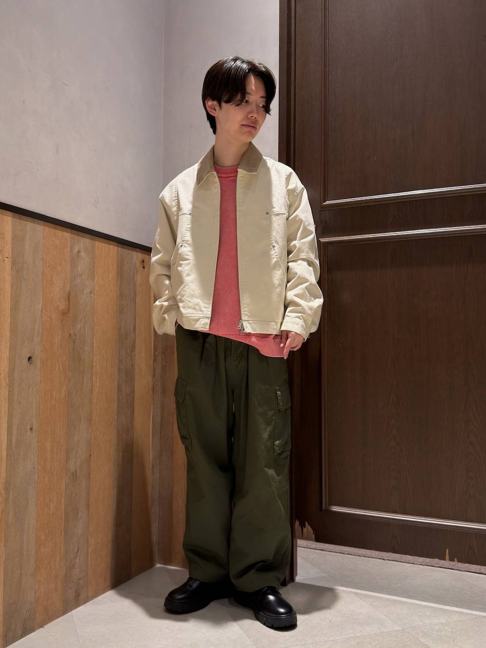 ブラック系のドレスシューズ、グリーン系のカーゴパンツ、ピンク系のニット/セーターを着用したメンズの春コーディネートの4枚目の写真