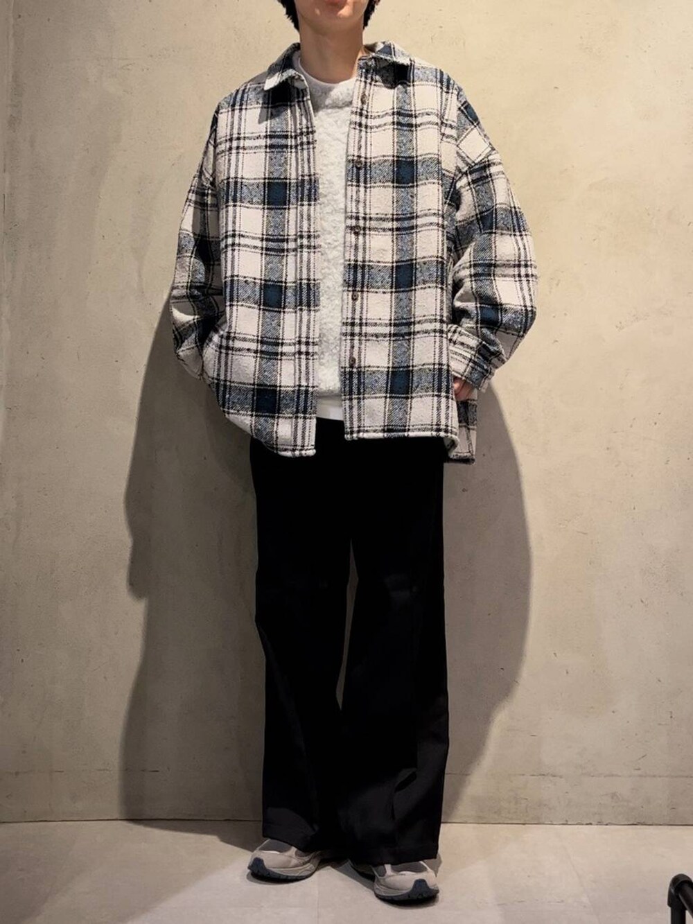 ブラック系のスラックス、ホワイト系のニット/セーター、グレー系のシャツ/ブラウスを着用したメンズの秋コーディネートの2枚目の写真