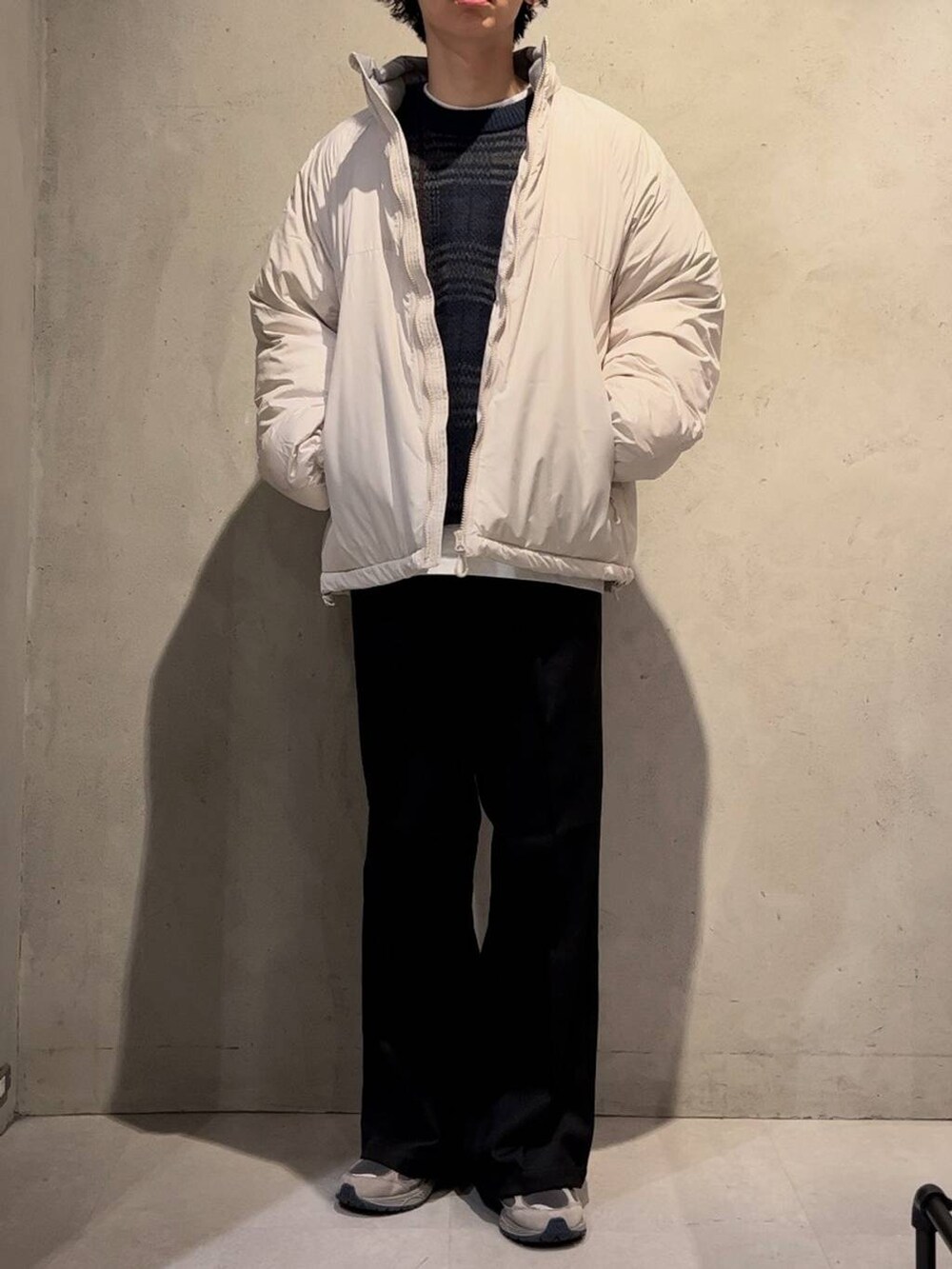 ホワイト系のダウンジャケット/コート、ブラック系のスラックス、ブルー系のニット/セーターを着用したメンズの秋コーディネートの2枚目の写真