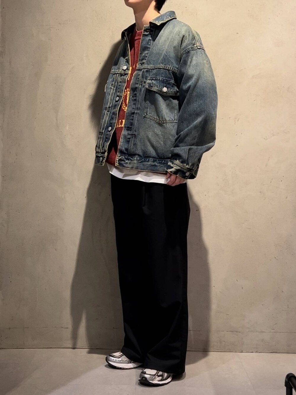 ブラック系のスラックス、レッド系のニット/セーター、ブルー系のデニムジャケットを着用したメンズの冬コーディネートの2枚目の写真