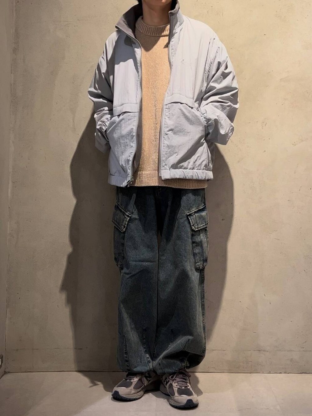 グレー系のブルゾン、ブルー系のデニムパンツ、ブラウン系のニット/セーターを着用したメンズの秋コーディネートの2枚目の写真