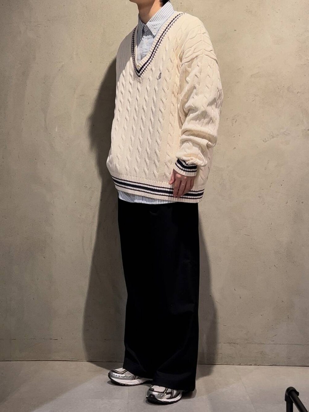 ブラック系のスラックス、ブルー系のシャツ/ブラウス、ホワイト系のニット/セーターを着用したメンズの冬コーディネートの2枚目の写真