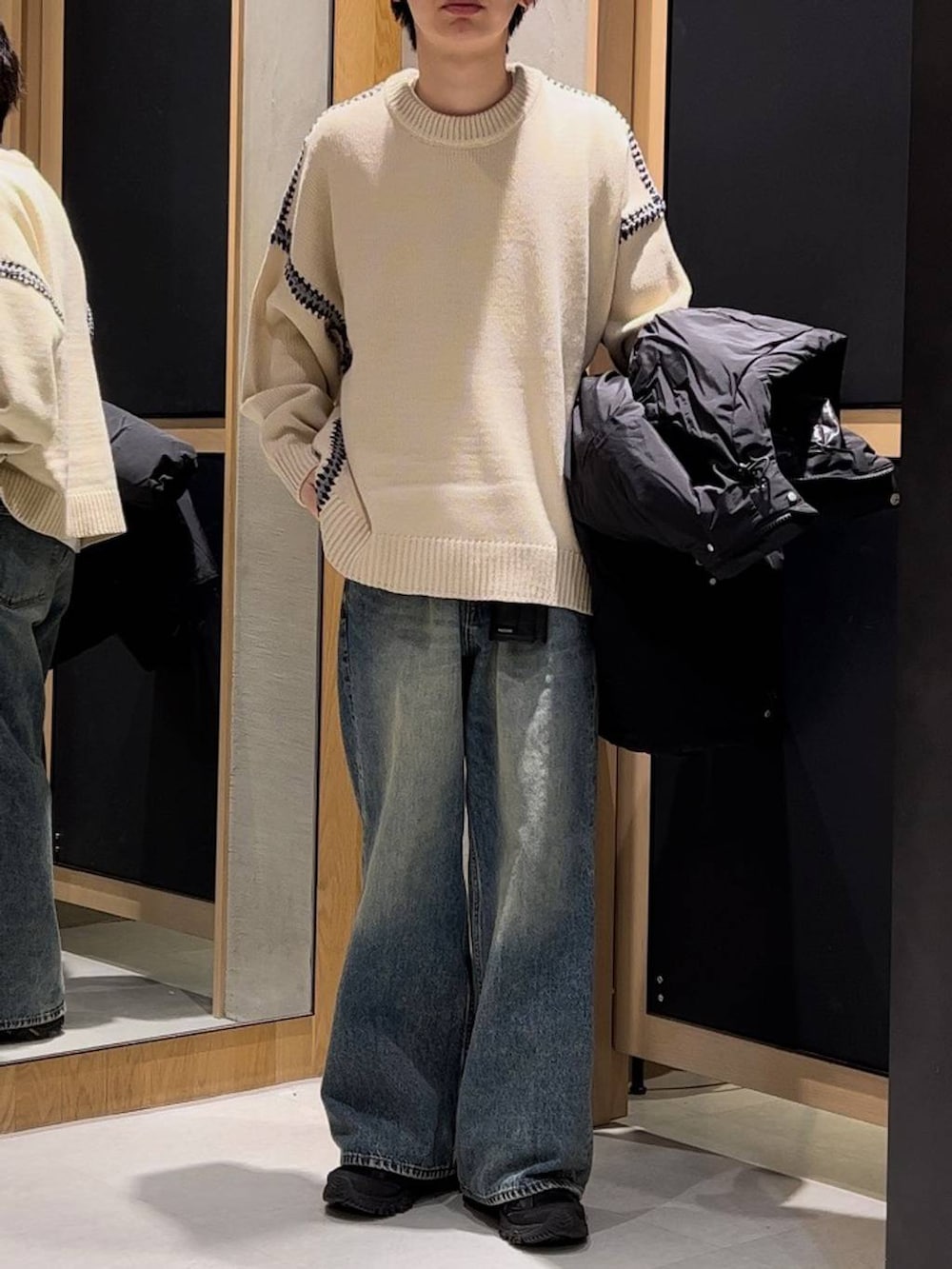 ブラック系のダウンジャケット/コート、ホワイト系のニット/セーター、ブルー系のデニムパンツを着用したメンズの冬コーディネートの2枚目の写真