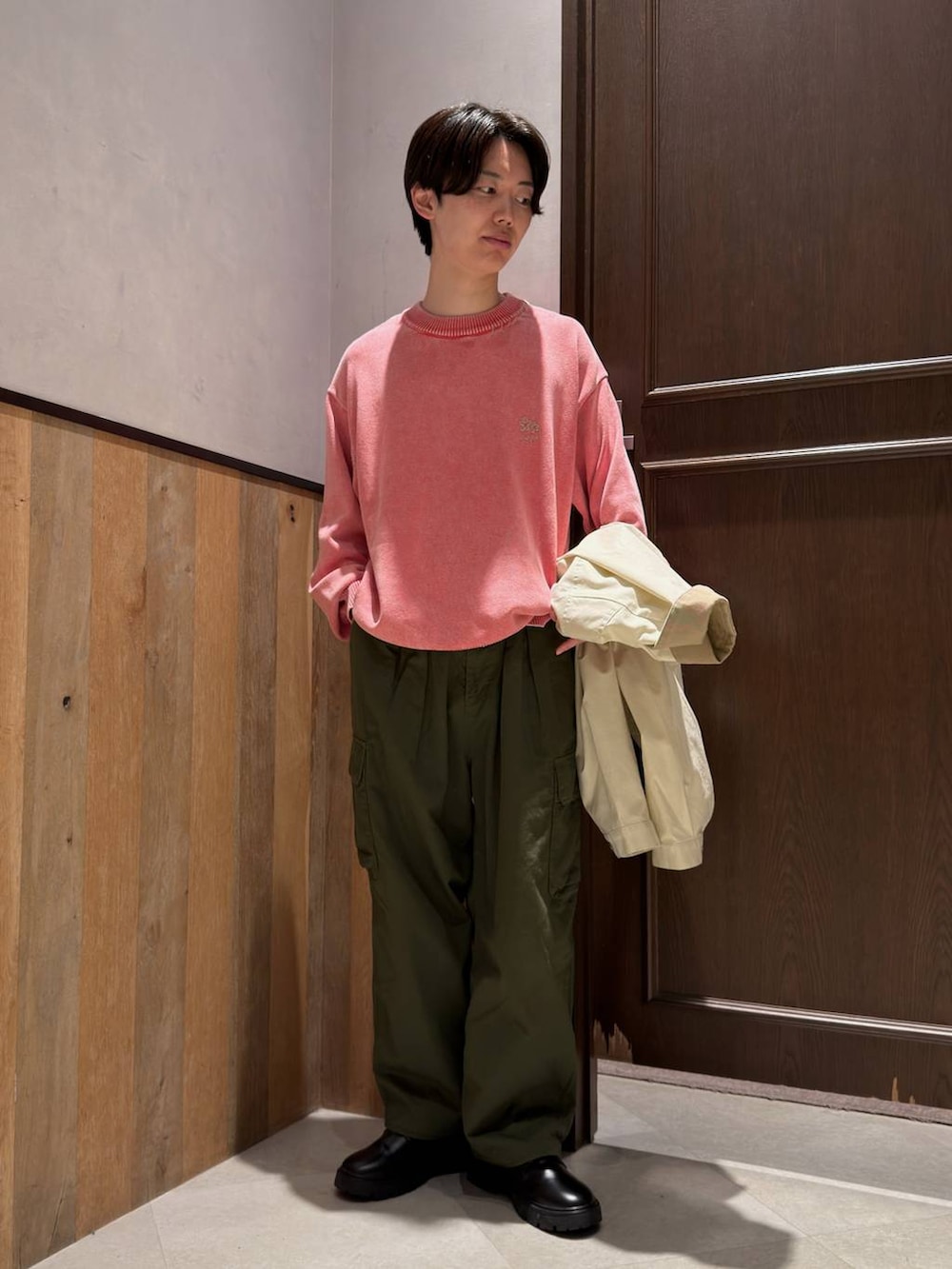 ブラック系のドレスシューズ、グリーン系のカーゴパンツ、ピンク系のニット/セーターを着用したメンズの春コーディネートの2枚目の写真