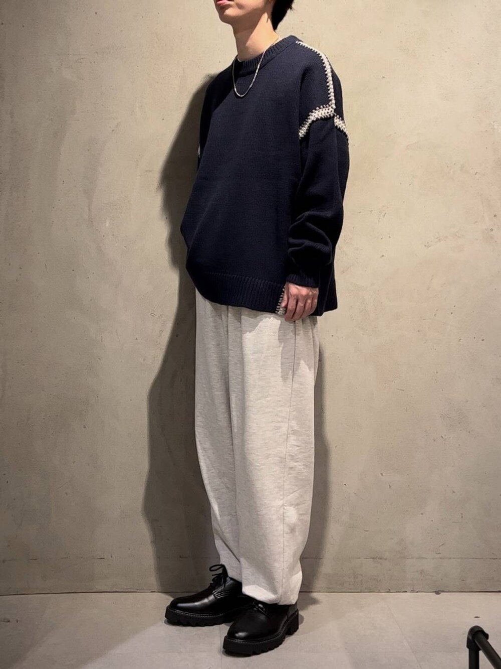 ブラック系のドレスシューズ、ブルー系のニット/セーター、その他のスウェットパンツを着用したメンズの秋コーディネートの2枚目の写真