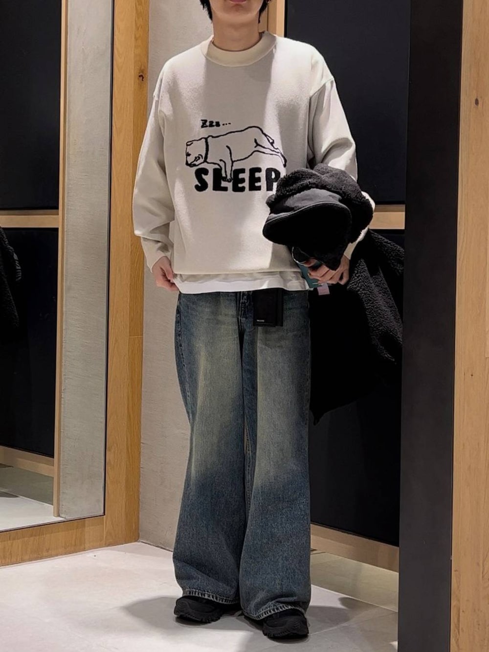 ブラック系のブルゾン、ホワイト系のニット/セーター、ブルー系のデニムパンツを着用したメンズの冬コーディネートの2枚目の写真