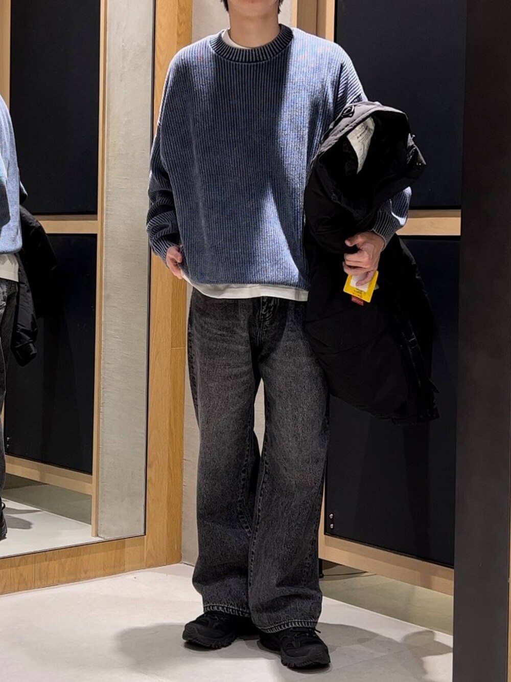 ブラック系のブルゾン、ブルー系のニット/セーター、グレー系のデニムパンツを着用したメンズの冬コーディネートの2枚目の写真