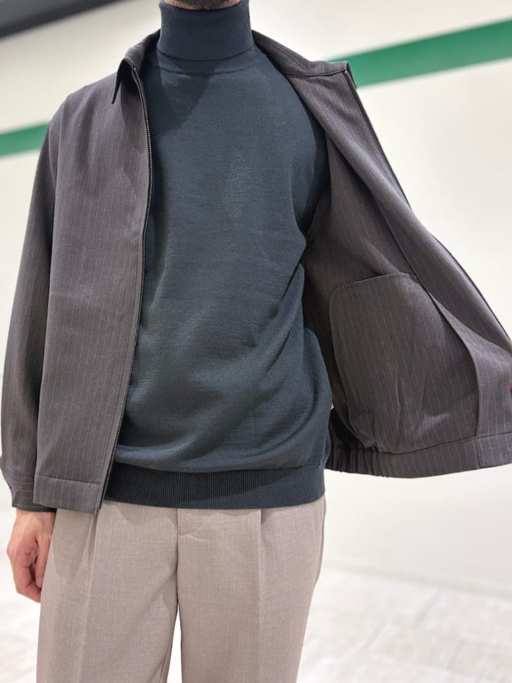 ベージュ系のスラックス、グレー系のニット/セーター、グレー系のブルゾンを着用したメンズの冬コーディネートの4枚目の写真