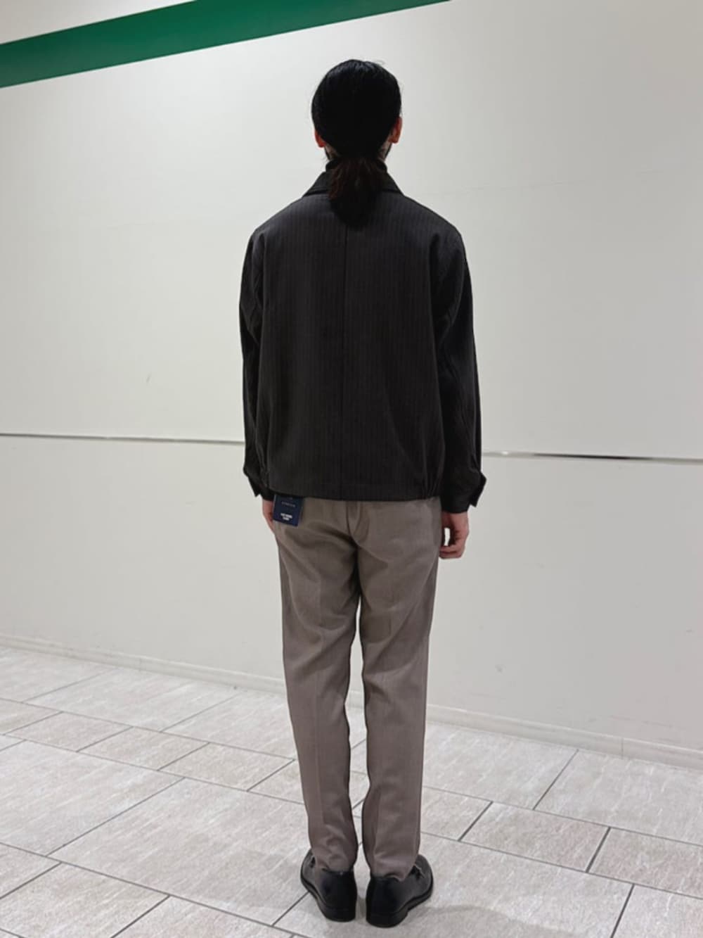 ベージュ系のスラックス、グレー系のニット/セーター、グレー系のブルゾンを着用したメンズの冬コーディネートの3枚目の写真